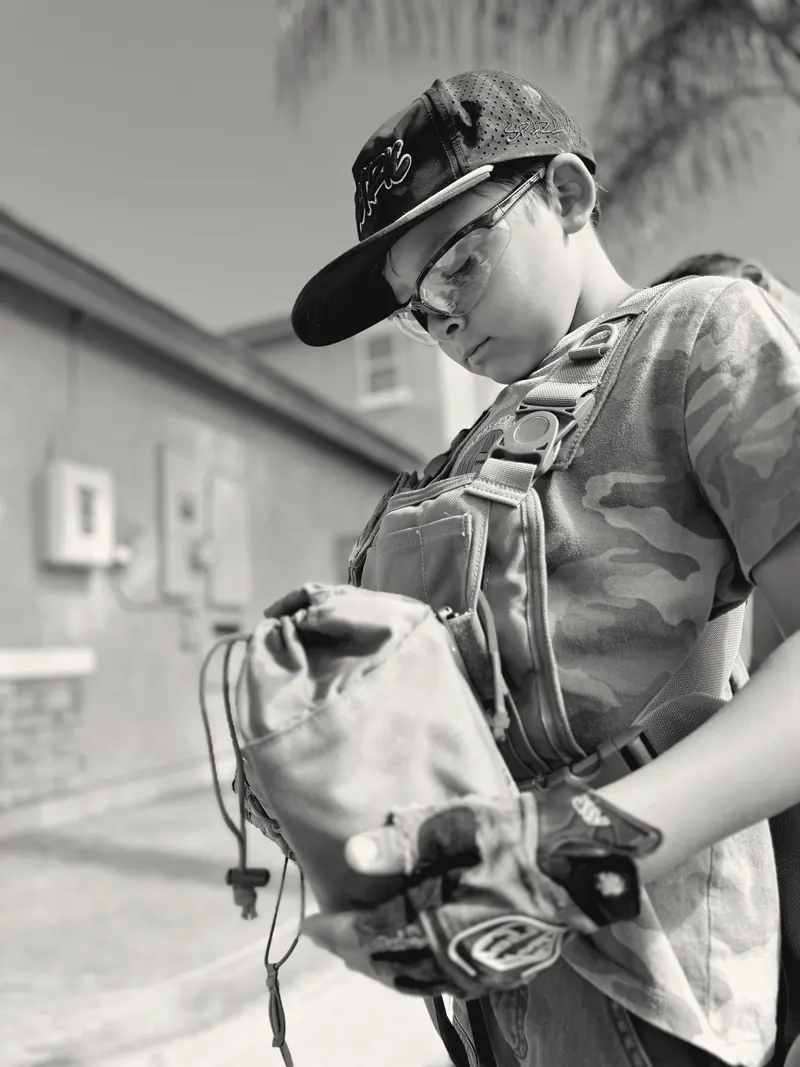 A participant in a cap, safety glasses and gloves opening a tool pouch