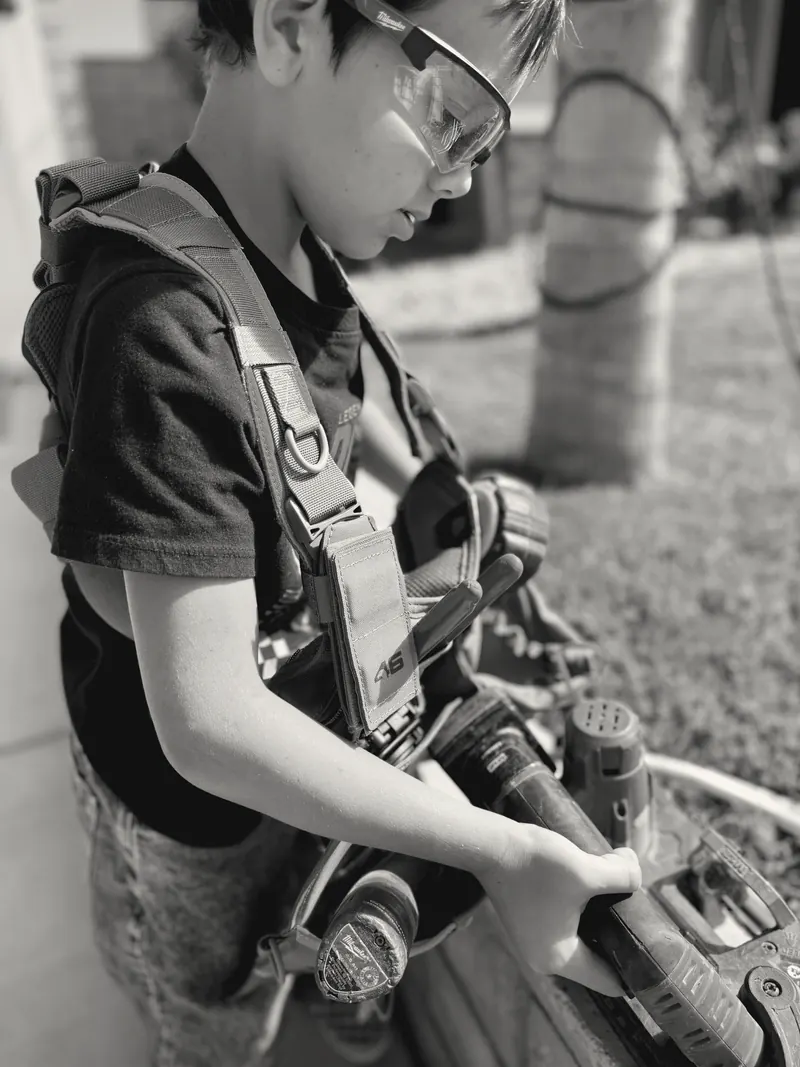 A participant in a tool vest and safety glasses working with a cordless tool
