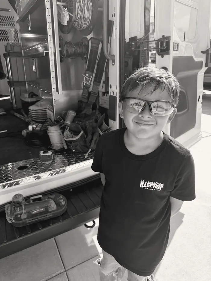 A smiling young participant in safety glasses at the work van