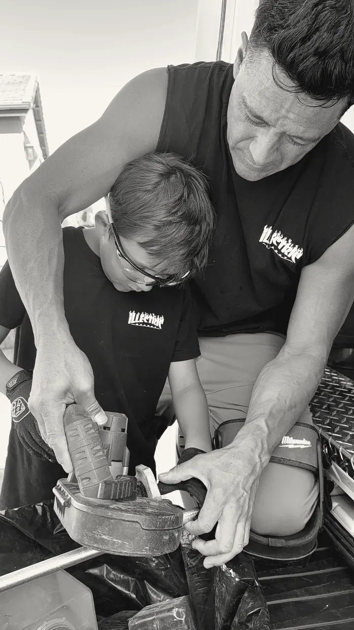 Joe guiding a young participant through a cut with a portable band saw