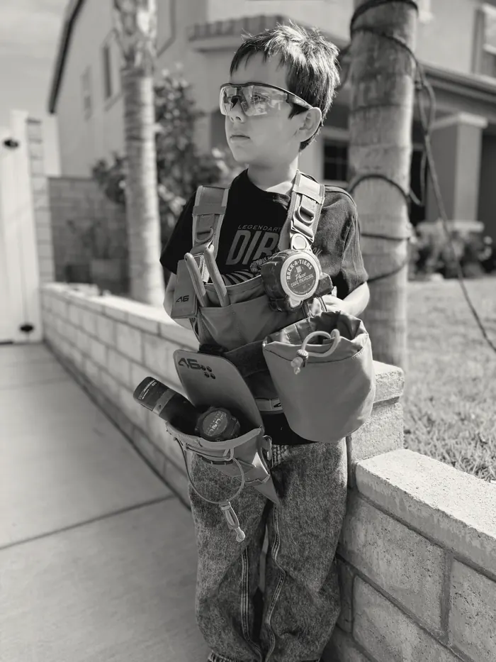 A young participant in safety glasses and a loaded tool vest